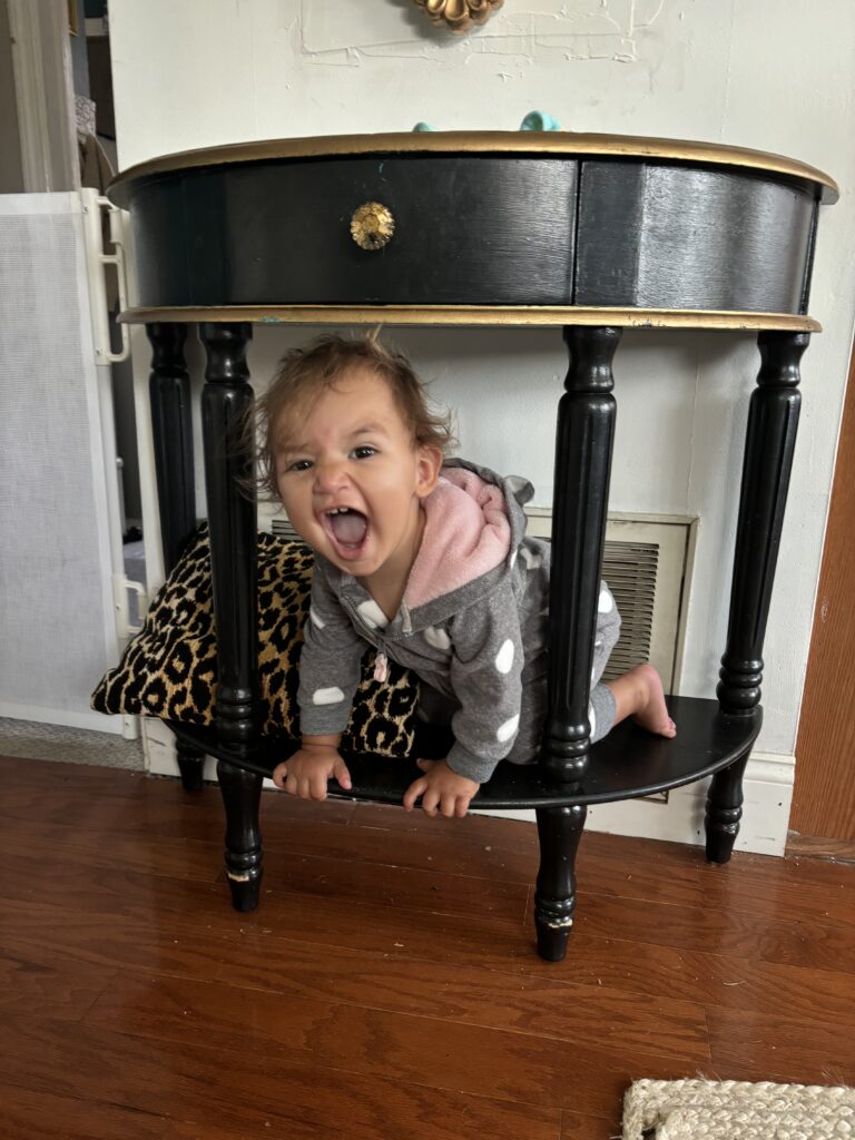 Baby girl sits on the shelf of a black console table