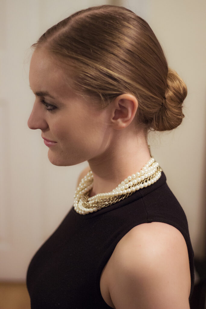 woman in black top with pearl necklace