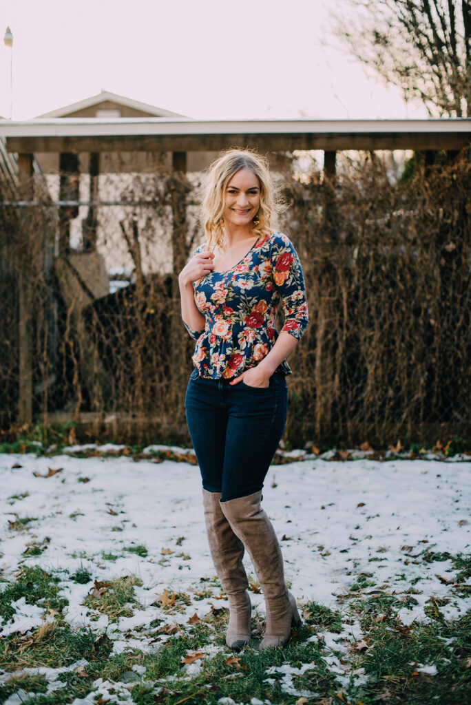 Woman in floral peplum top, jeans, and thigh high grey boots