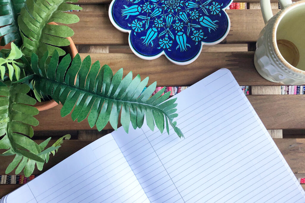 Open journal, plant, and cup of coffee