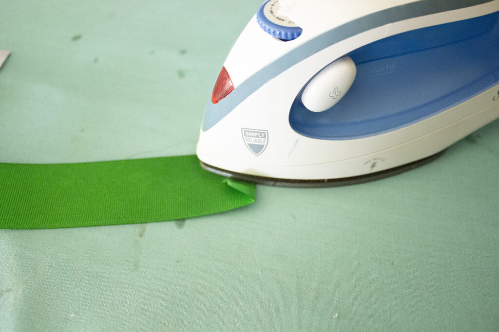 Ironing a fold into a green ribbon