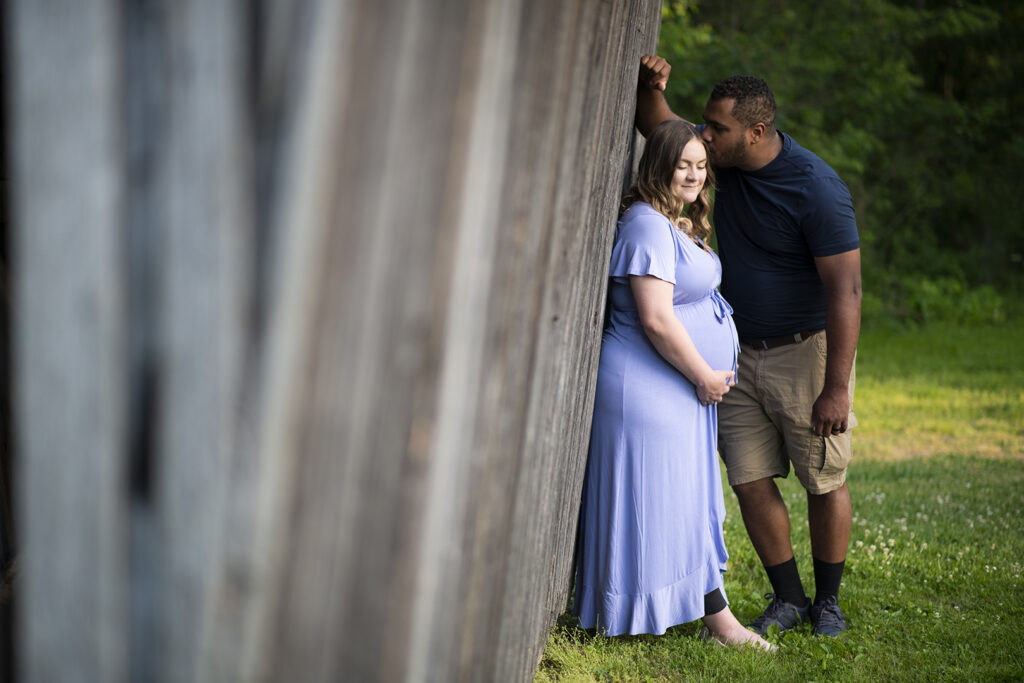 Affordable Maternity Clothes: Pregnant woman in a blue dress with husband kissing forehead