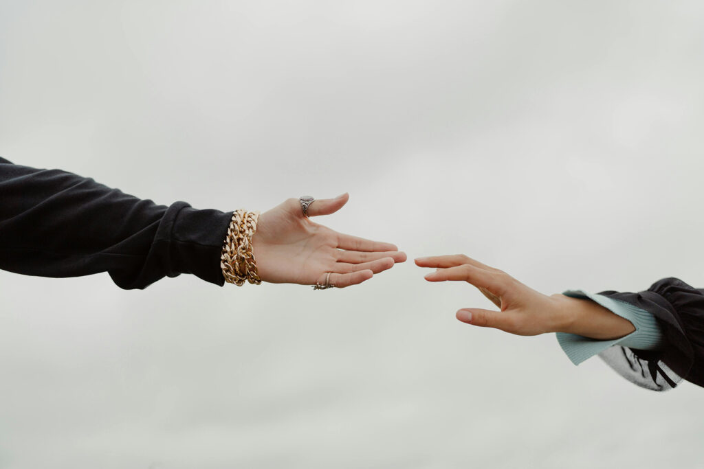 Reconciling in Christ: Two women's hands reaching out for each other