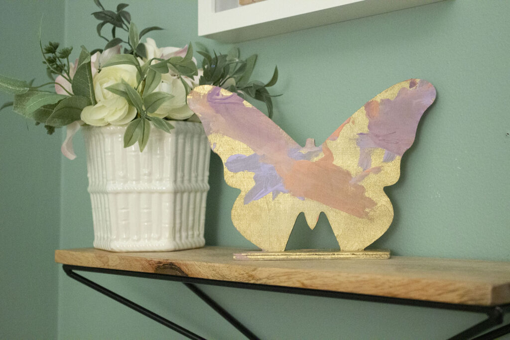 Shelf with wooden butterfly and floral arrangement