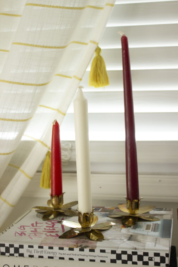three red and white taper candles in brass candleholders