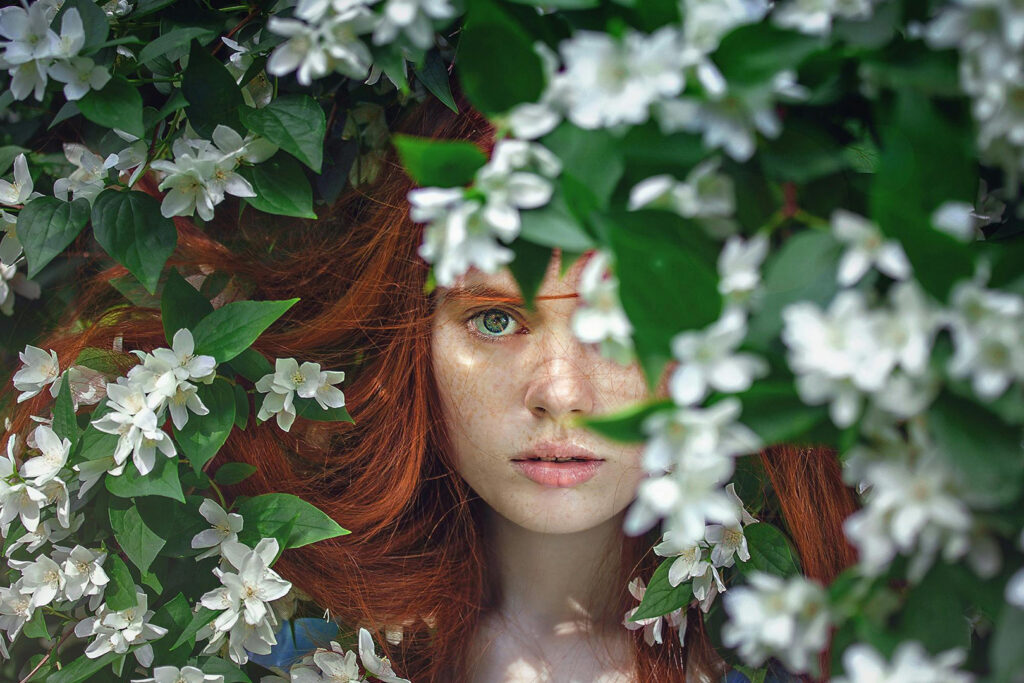 How to Stop Being a People Pleaser: Woman peeking out from a floral bush