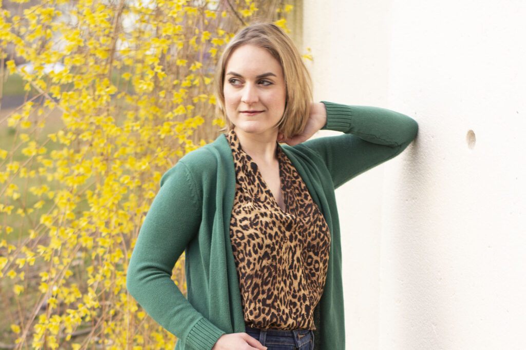 How to Be Content with Being Single: Smiling Woman in leopard top and green cardigan in front of yellow floral bushes